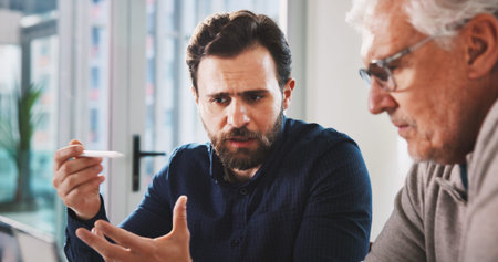 Men, discussion or talk in office with problem solving, guidance or plan for financial risk. Serious, business and people in company with crisis management, mentorship or advice for stock market.の写真素材
