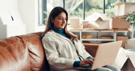 Moving, woman and research on laptop, new house and browsing renovation ideas on website and online. Calm, homeowner and person with tech for interior design, boxes and remodeling inspiration in homeの写真素材