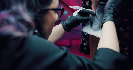 Tattoo, stencil and hands with artist in store for body art design, studio and culture. Permanent...