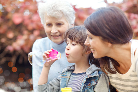 Grandma, mother and child blowing bubbles at park together, love or generation connection in...