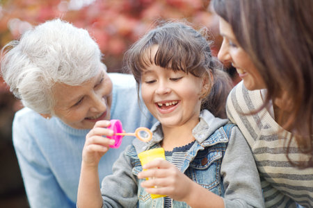 Grandmother, mother or child with bubbles at park together, love or generation connection in...