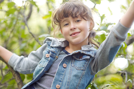 Happy, portrait and child playing in tree, climbing and outdoor activity for coordination...