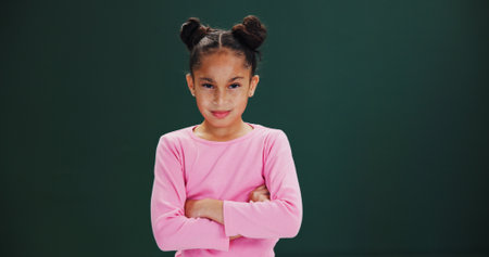 Portrait, girl and child with arms crossed in studio, assertive and confident pose on mockup space. Pride, freckles and kid with attitude, emoji and determined expression on green background.の写真素材