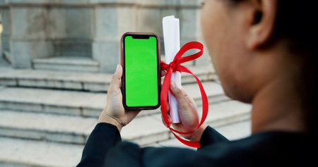 Hands, graduation and phone with green screen, diploma or mockup space for education at college. Person, student and certificate with mobile app ux, achievement and celebration for goal at universityの写真素材