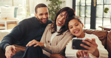 Parents, girl and selfie on sofa with love, smile and bonding for memory in living room at house. People, photography and happiness for profile picture, post for love and social media at family homeの写真素材