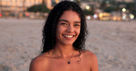 Happy, sunset and portrait of woman on beach for tropical vacation, getaway or holiday. Smile, travel and female person from Mexico by ocean for seaside weekend trip with peace and calm in evening.の写真素材