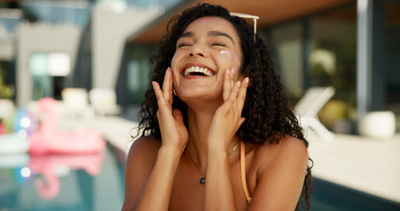 Sunscreen, swimming pool and woman at hotel in summer with facial moisturizer for protection of uv rays. Happy, dermatology and female person with spf face cream or lotion at holiday home for travel.の写真素材