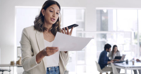 Phone call, paperwork and woman on loudspeaker in office, renewal agreement or deal negotiation for client. Coworking, mobile and contract manager with voice note, feedback or changes for partnershipの写真素材