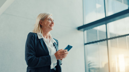 Office, lobby and woman with phone for business trip, smile and online communication. Travel, mature person and accommodation review with mobile app for schedule, meeting booking and confidenceの写真素材