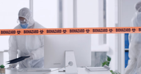 Biohazard tape, risk and people in office for safety, cleaning and warning for virus outbreak. PPE, hazmat suit and team with barrier for emergency, caution and crisis with danger, service and alertの写真素材