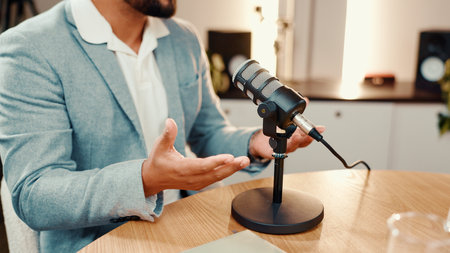 Hands, microphone and podcast with man in studio for broadcast, interview or live streaming. Radio, subscription entertainment and talk show host at table in production office for presentingの写真素材
