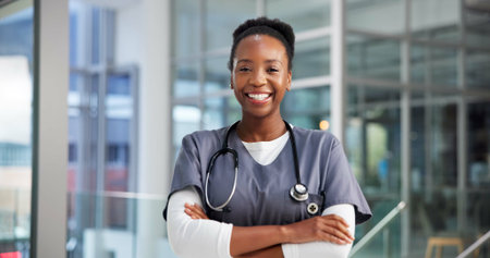 Portrait, black woman and doctor with arms crossed in hospital for career pride, healthcare service. Happy, person and ambition of medical support, cardiology surgeon and wellness clinicの写真素材