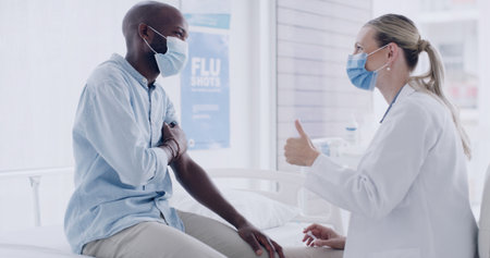 Healthcare, face mask and doctor with man in hospital for consultation with immunization shot. Thumbs up, checkup and medical worker with male patient for injection, medicine or medication in clinic.の写真素材