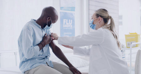 Injection, doctor or man with flu vaccine in clinic for illness prevention, immune booster or health. Healthcare mask, professional or patient on hospital bed for influenza shot, immunization or helpの写真素材