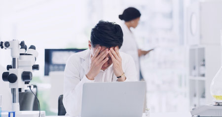 Man, scientist or laptop with headache in laboratory for forensic research, fail or mistake. Male person, healthcare worker or science with stress on computer for strain, pressure or medical deadlineの写真素材