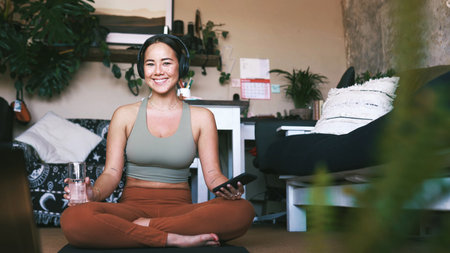 Home, portrait and water with woman, yoga and smile with smartphone, relax and exercise. Apartment, yogi and healthy person on floor, happiness and wellness with routine, hydration and liquidの写真素材
