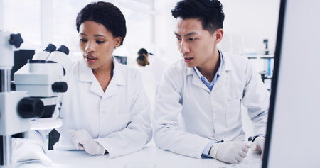 Medical, check or people in clinic with microscope, help or examination for vaccine development. Collaboration, research or scientist in lab with equipment, result or analysis in pharmaceutical studyの写真素材