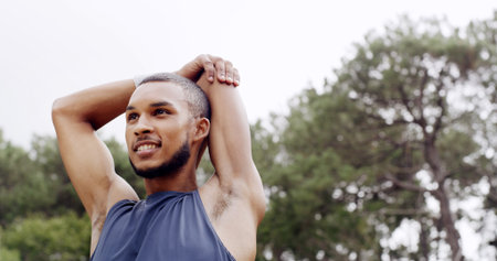 Fitness, stretching and man outdoor in nature for exercise, space and training with a smile. Male athlete, start arm muscle warm up and happy at park for workout, wellness and thinking of healthの写真素材