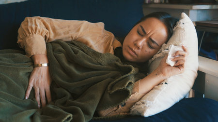 Home, sick and woman on sofa, stomach pain and menstrual cramps in living room. Apartment, bowel ache and person on couch, resting and ibs with constipation, endometriosis and diarrhea with virusの写真素材