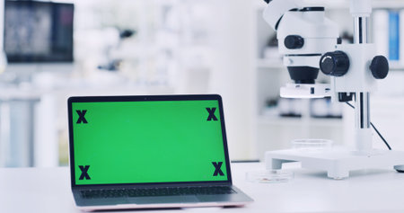 Laptop, green screen and microscope in lab for research, medical study and testing sample. Equipment, pc and biotechnology for experiment, mockup space and online results for vaccine developmentの写真素材