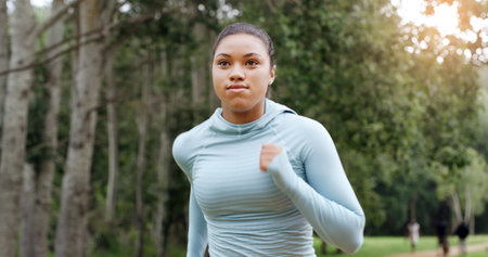 Woman, running and outdoor for fitness in park, training routine and speed for cardio challenge at sunset. Girl, athlete and perspective for workout, exercise or jog in nature for wellness in summerの写真素材