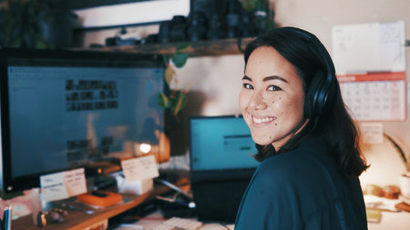 Headphones, computer and portrait of businesswoman in office with listening to music, podcast or radio. Happy, desktop and Asian female creative editor with audio tech for streaming playlist online.の写真素材