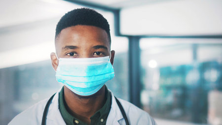 Portrait, doctor or man in hospital with mask for healthcare consultation or protection from infection. Medical professional, black person or PPE for safety compliance, wellness or spread of disease.の写真素材