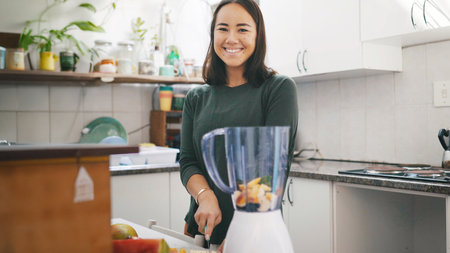 Portrait, woman and fruit for blender, kitchen and happy for gut health benefits, wellness and detox. Cutting, ingredients and person with machine for smoothie, nutrition or diet with protein in homeの写真素材