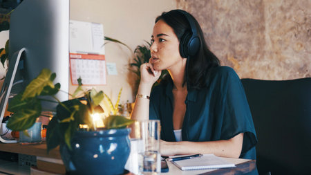 Remote work, headphones or woman with computer in home office, planning or thinking for creative project. Research, news article and journalist contemplating ideas for publication, tech or freelancerの写真素材