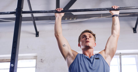 Workout, pull up bar and fitness with man in gym for arm exercise, health and challenge. Strength training, bodybuilder and low angle with person in sports club and equipment for athlete and strongの写真素材