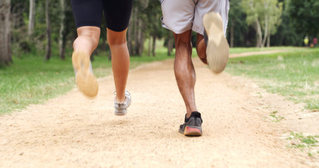 Fitness, legs and back of couple running in forest for health, wellness or training outdoor. Man, woman and shoes of trail runner in woods for cardio workout, endurance exercise or practice in natureの写真素材