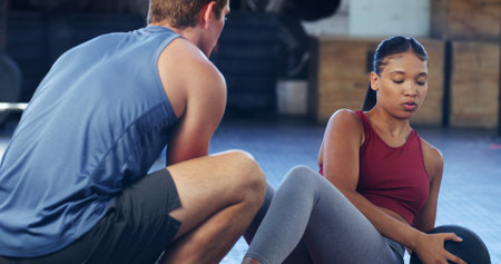 Coaching, medicine ball and workout with woman in gym for ab exercise, health and challenge. Strength training, personal trainer and fitness with person in sports club and equipment for athleteの写真素材