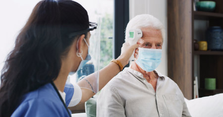 Healthcare, mask or thermometer with nurse and old man on sofa in home living room for checkup. Appointment, ppe or temperature with caregiver and senior patient in apartment for medical diagnosisの写真素材
