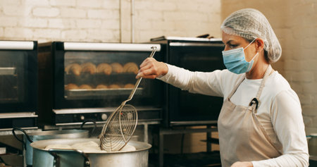 Mask, baker or frying donuts in kitchen for dessert production, baking process or catering....
