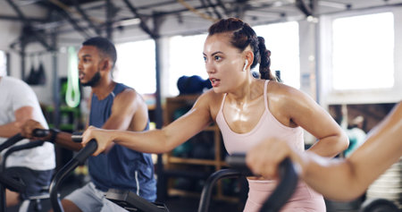 Spin class, exercise and earphones with woman in gym for intense workout, music and cycling...