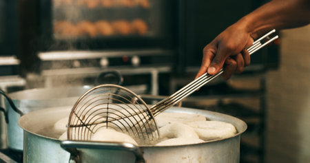 Hands, baker or tool for frying donuts in kitchen for breakfast order, baking process or gastronomy. Catering, person or strainer in bakery for small business, snack production or dessert preparationの写真素材