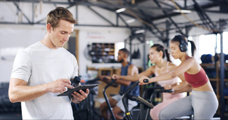 Man, instructor and tablet with people in spin class for fitness results, schedule session and...