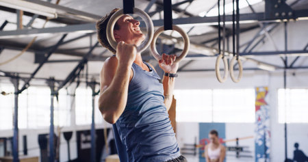 Smile, man and pull up with gymnastics rings for fitness, exercise and training for body strength. Male person, equipment and intense workout for weightlifting, muscle endurance and power challengeの写真素材