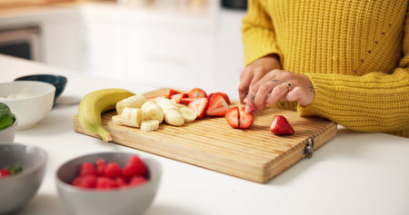 Person, hands and cutting strawberry with board in kitchen for smoothie, nutrition or meal prep. Closeup, health or nutritionist with ingredients or organic fruit for dietary, wellness or vitaminsの写真素材