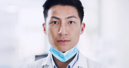 Portrait, medical research and man in lab, science and experiment with face mask. Asian person, scientist and employee in workplace, safety and biologist with pride, confidence and protectionの写真素材