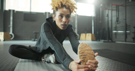 Stretching, leg and woman in gym, fitness and getting ready for workout routine, wellness and health. Flexible, athlete and person on floor for exercise preparation, physical activity and warm upの写真素材