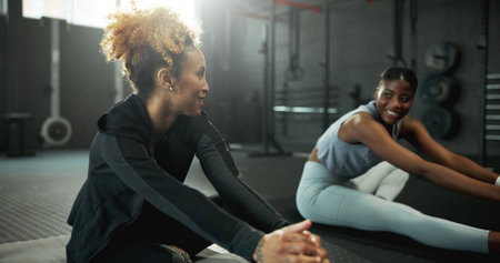 Stretching, leg and women in gym, healthy and getting ready for workout routine, wellness or fitness. Flexible, athlete and people on floor for exercise preparation, physical activity and warm upの写真素材