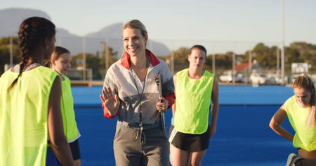 Field hockey, talking and coach with women outdoor for training, practice and match strategy. Sports hobby, fitness and people on turf with exercise for playing game, competition and tournamentの写真素材