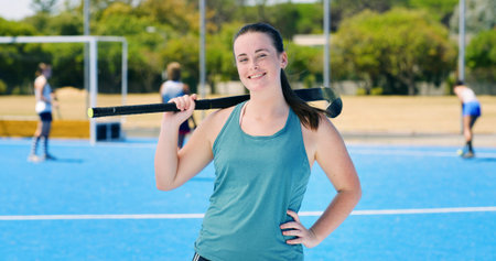 Portrait, hockey stick and woman with smile, training and fitness with competition. Happy person, player and healthy athlete with exercise, practice and confidence with equipment, workout and outdoorの写真素材