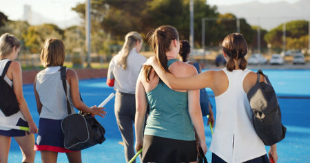 Walking, field hockey and back of women outdoor to start training, practice and exercise. Team, hug and people in conversation ready for playing match, game and tournament on turf for sports hobbyの写真素材