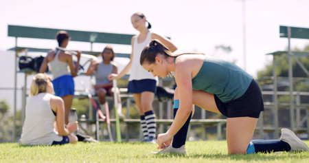 Woman, fitness and tying with shoe for sport, hockey game or outdoor preparation on grass field. Active, female person or player getting ready with tie or sneakers for match, training or practiceの写真素材