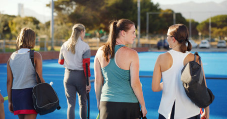 Sports, hockey and women outdoor with coach talking for training, practice and exercise. Team, happy and back of people in conversation for playing match, game or tournament on turf for fitness hobbyの写真素材