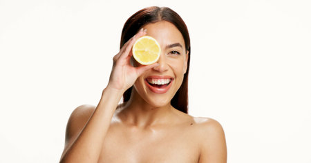 Studio, portrait and woman with lemon, skincare and happiness for collagen boost or facial treatment. White background, space and person with fruit for natural cosmetics, vitamin c and dermatologyの写真素材