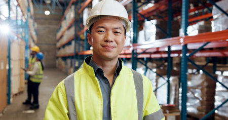 Portrait, industrial engineer and man in warehouse, happy and pride for distribution of supply chain. Shipping, goods and person with helmet for safety, logistics and smile for production in factoryの写真素材