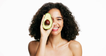 Beauty, avocado and portrait of woman in studio with hydration, natural or cosmetics routine. Glow, skincare and female person with fruit for facial moisturizing and cleansing by white background.の写真素材